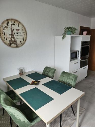 mesa de comedor con sillas y reloj en la pared en Ferienwohnung Monteurwohnung Majü, en Bremerhaven