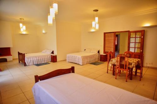 a room with two beds and a table and chairs at Sara Chambre d'hôtes in Antananarivo