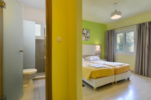 a yellow bedroom with a bed and a bathroom at Hotel Orpheus in Gouvia