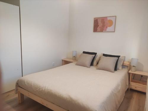 ein Schlafzimmer mit einem weißen Bett und zwei Kissen in der Unterkunft T1 Casa da Quinta in Mafra