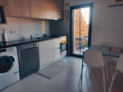 eine Küche mit einer Waschmaschine und einem Tisch mit Stühlen in der Unterkunft T1 Casa da Quinta in Mafra