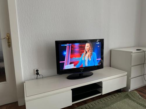 einen Flachbild-TV auf einem weißen Entertainment-Center in der Unterkunft Apartment in Hannover