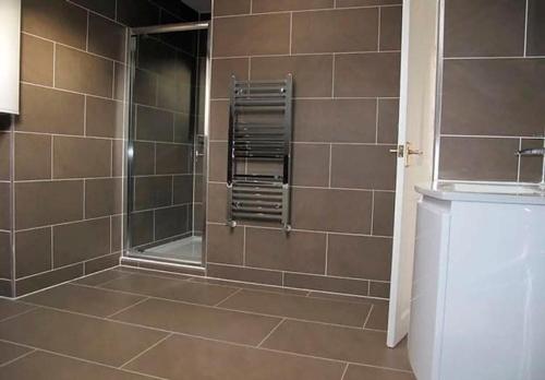Un baño con ducha con puerta de cristal. en Ivy House - Seafront house with garden seating and stunning sea views! - Ocholo Villas, en Filey