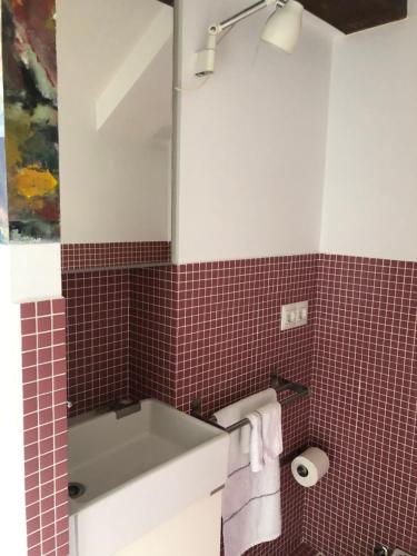 een badkamer met een wastafel en een rode tegelmuur bij Loft Adrimar in Santoña