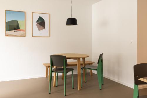 a table and chairs in a room with paintings at EMA House Serviced Apartments Aussersihl in Zürich