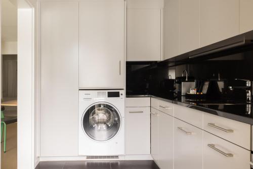 a white kitchen with a washing machine in it at EMA House Serviced Apartments Aussersihl in Zürich