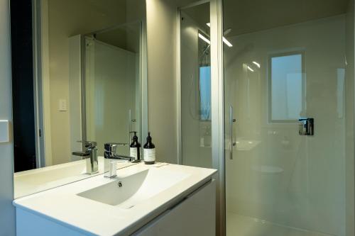 a bathroom with a sink and a shower with a mirror at Jacks Lodge Townhouse in Hanmer Springs