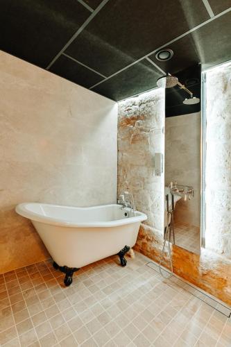a white bath tub in a bathroom with a sink at Nolcken Lagerhaus in Kuressaare