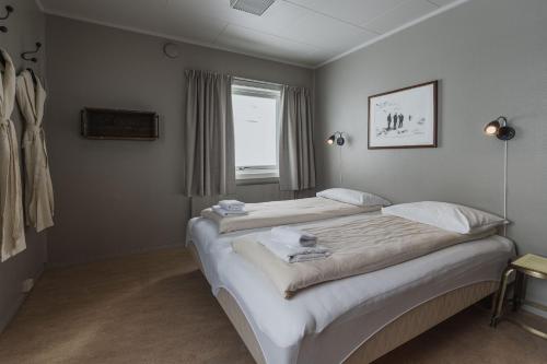 two twin beds in a room with a window at Coal Miners’ Cabins in Longyearbyen