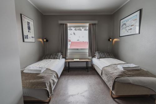 2 Betten in einem Zimmer mit Fenster in der Unterkunft Coal Miners’ Cabins in Longyearbyen