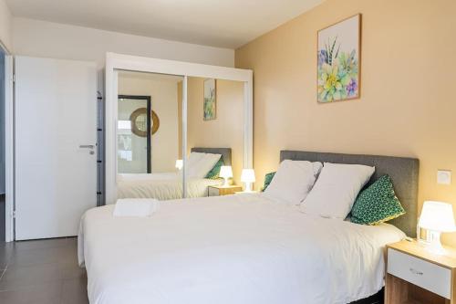 une chambre avec un grand lit blanc et un miroir dans l'établissement Le Barcelone, Beau T2, Clim, Terrasse,Centre ville, à Montpellier