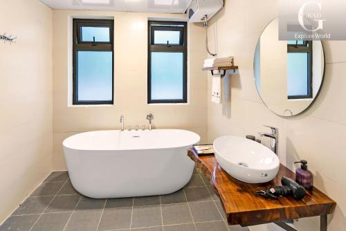 baño con bañera blanca grande y espejo en Cerf Volant Soc Son Resort, en Hanói