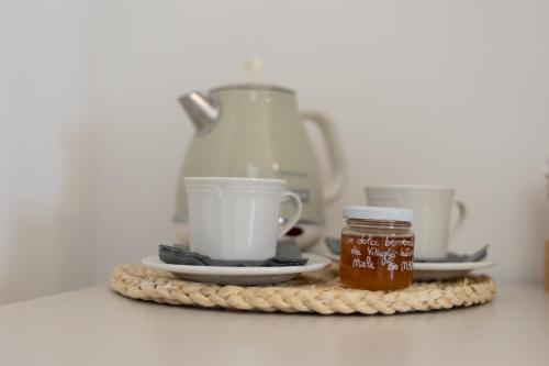 a tea pot and two cups and a jar of honey at Le Casette di Giò in Monteodorisio