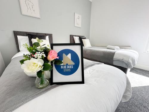 two beds with a vase of flowers and a sign on it at Wrightson House by Blue Skies Stays in Stockton-on-Tees