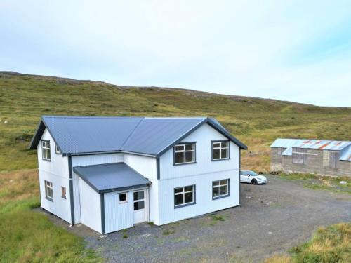 una casa blanca con un garaje en una colina en Lindarhóll Guesthouse, en Stóri-Bakki