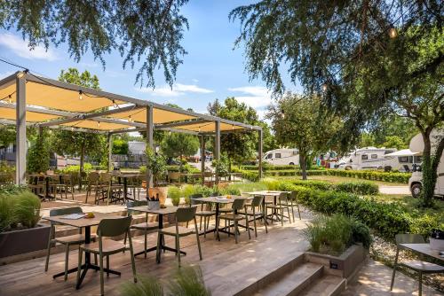 an outdoor patio with tables and chairs under a canopy at Maistra Camping Veštar Pitches in Rovinj
