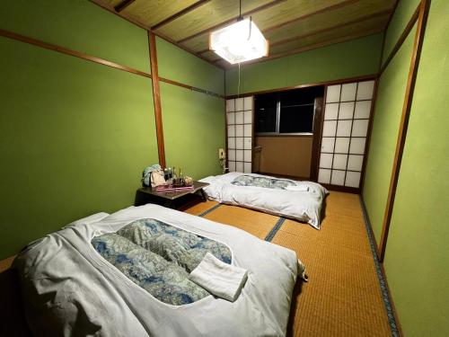 2 łóżka w pokoju z zielonymi ścianami w obiekcie 苗場 中村屋 w mieście Yuzawa
