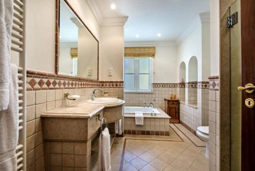 y baño con lavabo, bañera y espejo. en Villa Plaza - beautiful spacious house off roundabout 6 Quinta Do Lago en Quinta do Lago