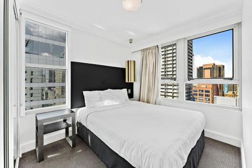 a bedroom with a large bed and two windows at AirCabin - Sydney CBD - Best Location -1 Bed Apt in Sydney
