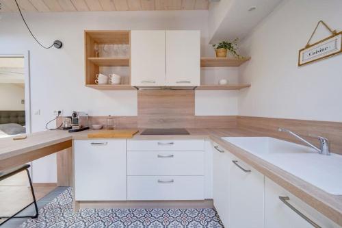 une cuisine avec des armoires blanches et un évier dans l'établissement Le Cosy, superbe appartement dans Saint Emilion, à Saint-Émilion