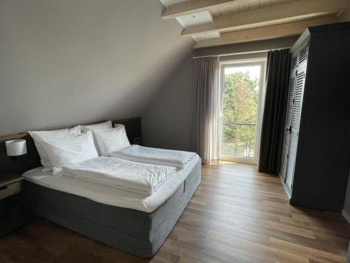 ein Schlafzimmer mit einem Bett und einem großen Fenster in der Unterkunft 4Hafenzeiten - Ferienwohnung NIE 9 Lotte in Timmendorfer Strand