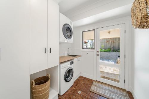 a white laundry room with a washer and dryer at The Grape Escape Location and style on Shiraz Trail in McLaren Vale