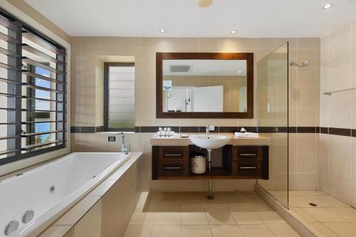 a bathroom with a tub and a sink and a mirror at Iririki Island Resort & Spa in Port Vila