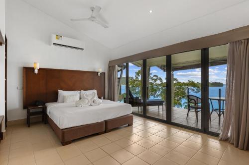 a bedroom with a bed and a balcony with a view at Iririki Island Resort & Spa in Port Vila