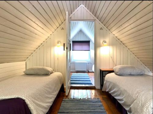 two beds in a room with a window and a staircase at Joosepi Holiday House in Silla
