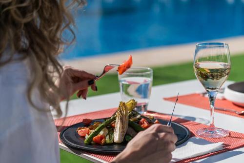 a woman eating a plate of food with a glass of wine at THB Maria Isabel - Adults Only in Playa de Palma
