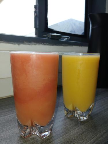 two glasses of orange and orange juice sitting on a table at Lovana apartments and hotel in Gulu