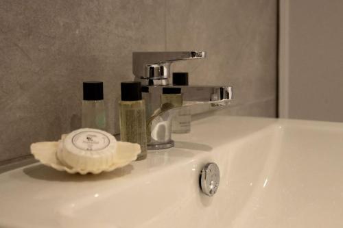a bathroom sink with a faucet with a timer and soap at KingsHouse In Cheam Village in Cheam
