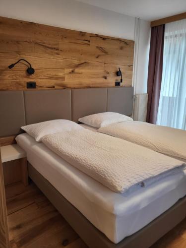 two beds in a bedroom with a wooden wall at Penzion Tavcar in Ljubljana