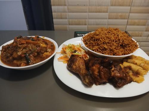 Gulu的住宿－Lovana apartments and hotel，两盘食物,餐桌上放有肉和米