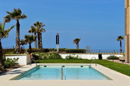 einen Pool mit Palmen und einer Brücke in der Unterkunft Pestana Casablanca, Seaside Suites & Residences in Casablanca