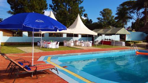a blue umbrella and a chair next to a pool at ATACO COUNTRY RESORT in Fort Portal