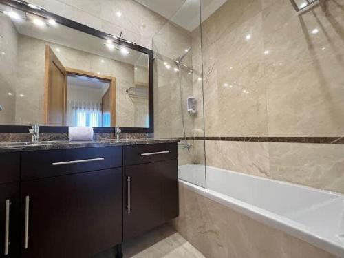 bagno con vasca, lavandino e specchio di Villa Pedra Luxe - Spacious modern villa ad Albufeira
