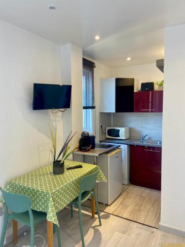 une cuisine avec une table et une cuisine avec des placards rouges dans l'établissement STUDIO VERT FSHH, à Nice