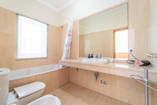 a bathroom with a toilet and a sink and a mirror at Villa Gale Grande - bright airy property with a private pool in Albufeira