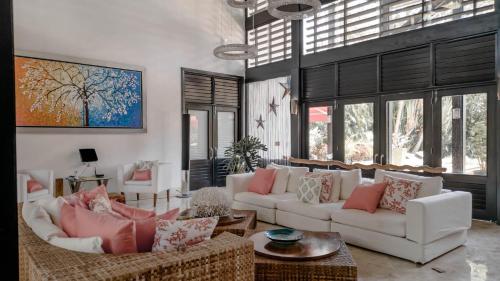 a living room with two white couches and windows at Casa de Campo 4-BR Retreat: Pool, Jacuzzi, Sauna, Chef & Maid in La Romana