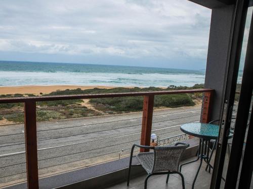 a balcony with a table and a view of the ocean at White Sands Self-catering units in Wilderness