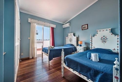 a blue bedroom with two beds and a window at Villa Almanda - Spacious villa perfectly located between Albufeira Marina and the Old Town in Albufeira