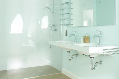 a white bathroom with two sinks and a shower at D’oude Dune in Nieuwpoort