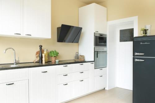 a kitchen with white cabinets and a black refrigerator at D’oude Dune in Nieuwpoort