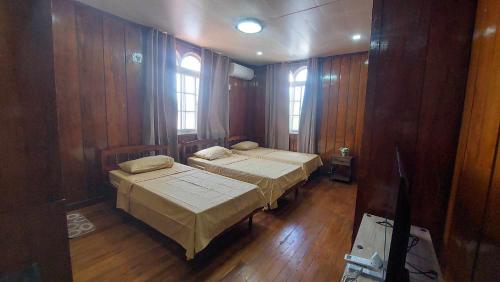 two beds in a room with wooden walls at Topaz Bed & Breakfast Hotel in San Jose