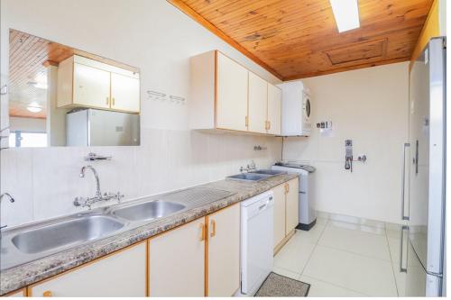 Una cocina con gabinetes blancos y un fregadero. en 17 Villa Leadwood, en Jeffreys Bay