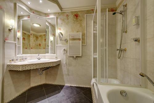 La salle de bains est pourvue d'une baignoire, d'un lavabo et d'une douche. dans l'établissement Strandhotel Nordischer Hof, à Kühlungsborn