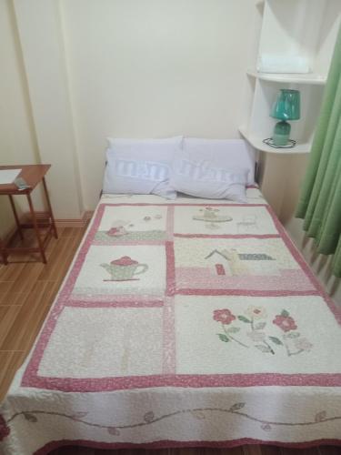 a bed with a pink and white quilt on it at bucana traveler's inn in Guinisiliban