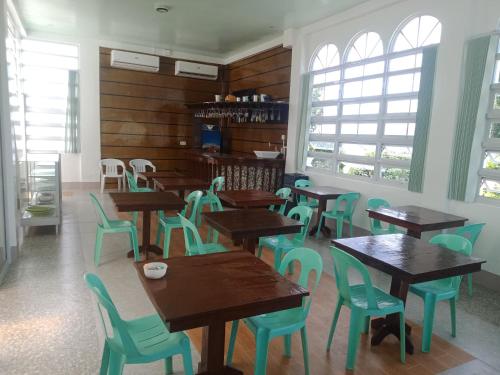 a restaurant with wooden tables and chairs and windows at bucana traveler's inn in Guinisiliban