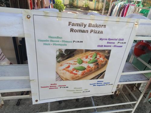 a sign for a family kitchens roman pizza at bucana traveler's inn in Guinisiliban